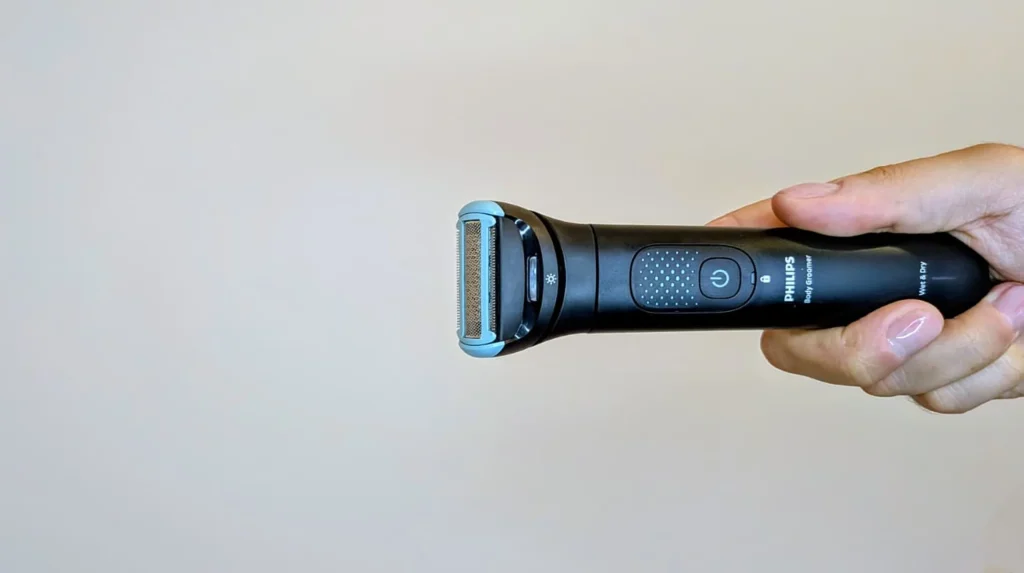 Máquina de depilação Philips Body Groomer segurada por uma mão.