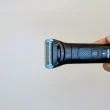 Máquina de depilação Philips Body Groomer segurada por uma mão.