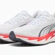 Sapatilhas de corrida Puma brancas com detalhes em vermelho.
