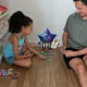 Homem e menina a jogar cartas no chão de madeira.