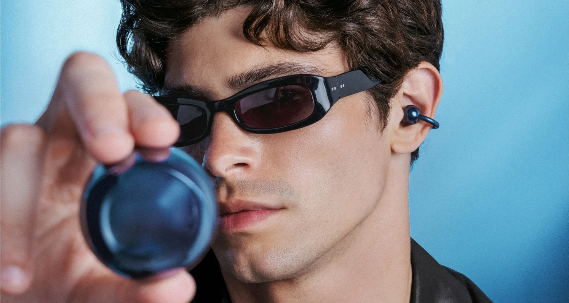 Homem com óculos de sol e auriculares azuis tecnológicos.