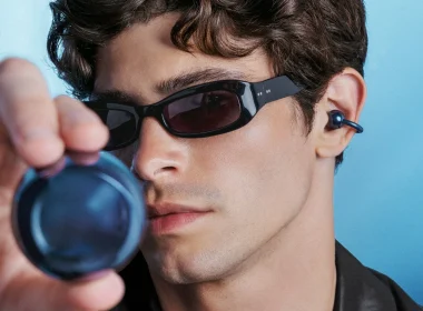 Homem com óculos de sol e auriculares azuis tecnológicos.