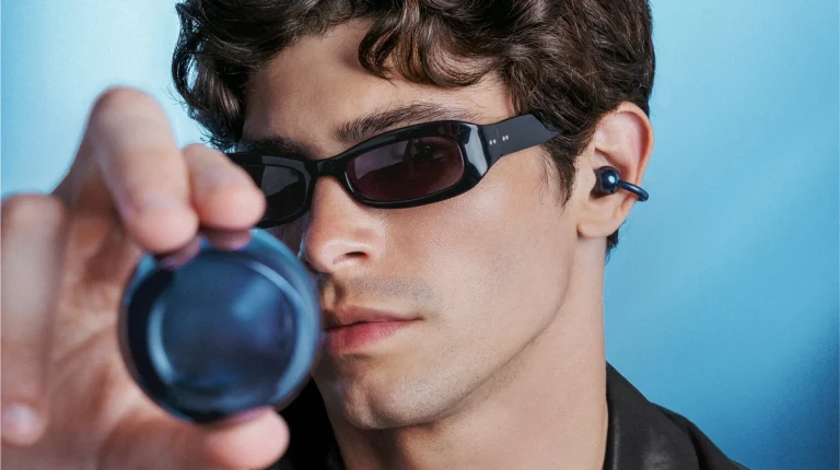 Homem com óculos de sol e auriculares azuis tecnológicos.