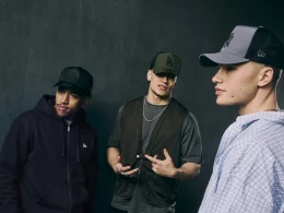 Três homens com bonés New Era num estilo streetwear urbano.