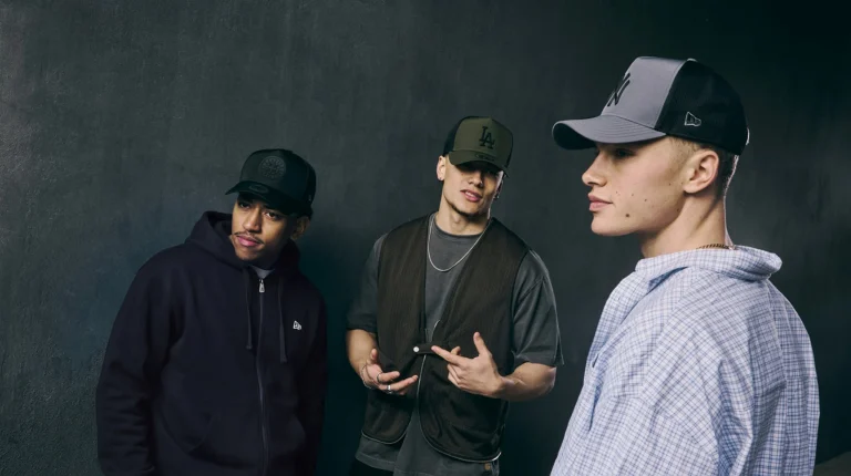 Três homens com bonés New Era num estilo streetwear urbano.