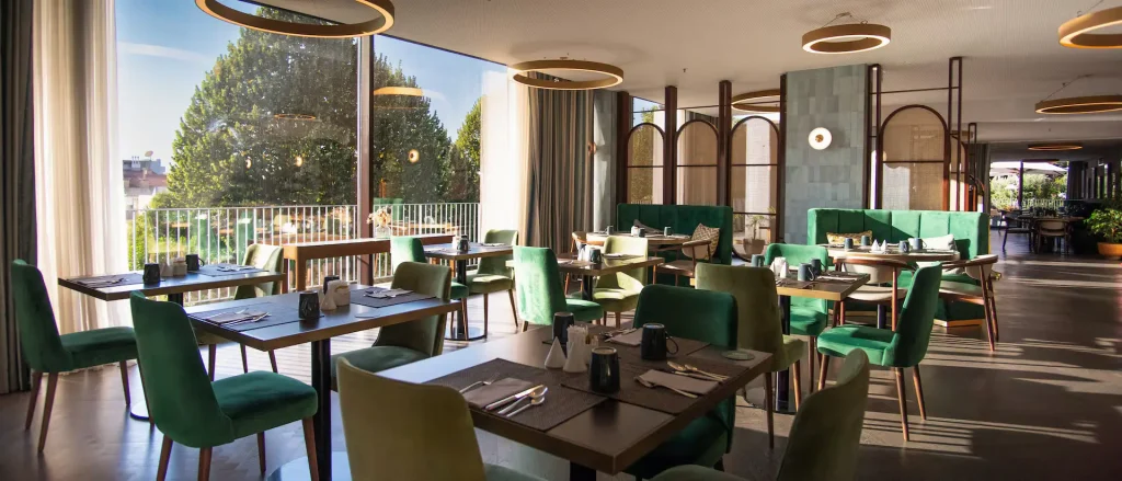 Restaurante moderno com mesas e cadeiras verdes.