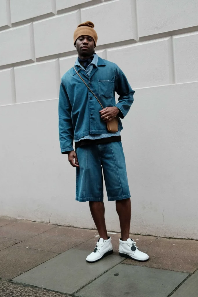 Homem com conjunto de ganga, gorro e sapatilhas brancas.