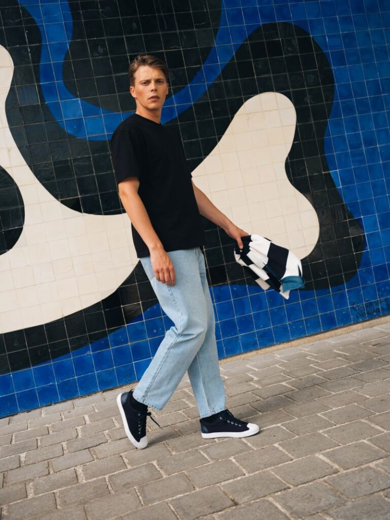 Homem com roupas casuais em frente a mural colorido.