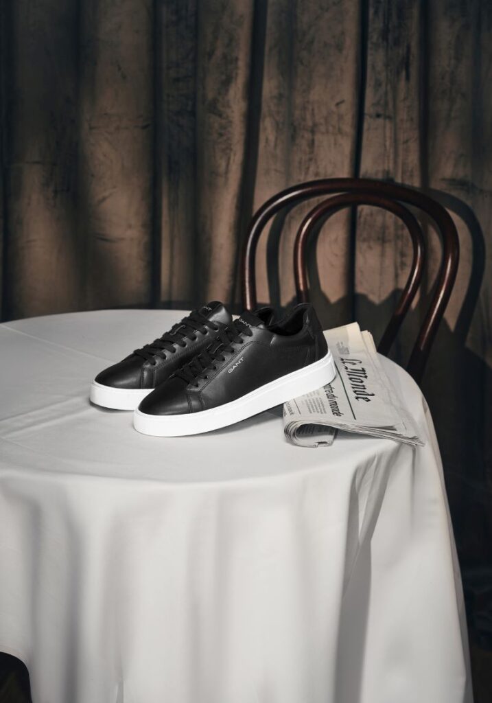 Sapatos pretos elegantes sobre mesa com jornal.