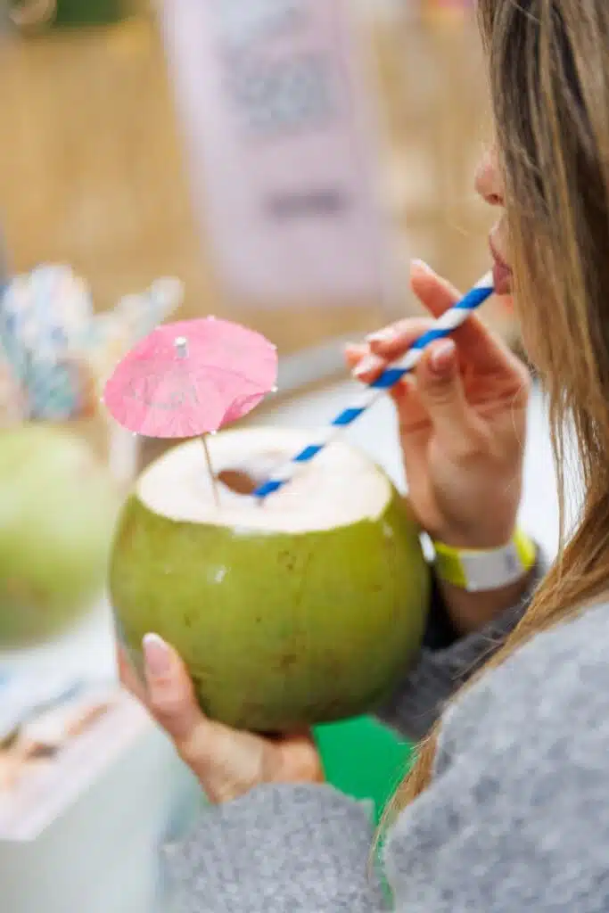 Pessoa bebendo água de coco com palhinha.