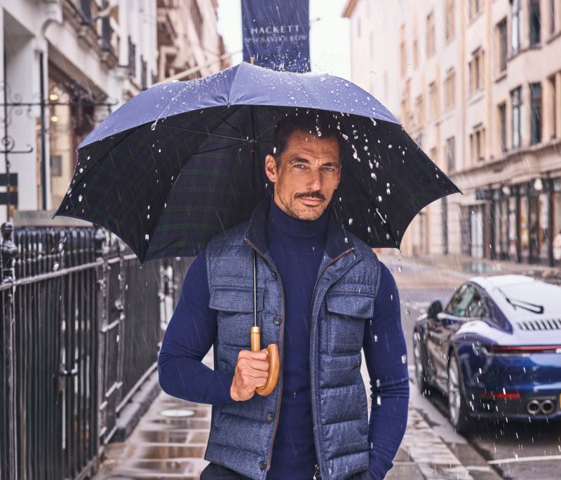 Homem elegante com guarda-chuva na chuva urbana.