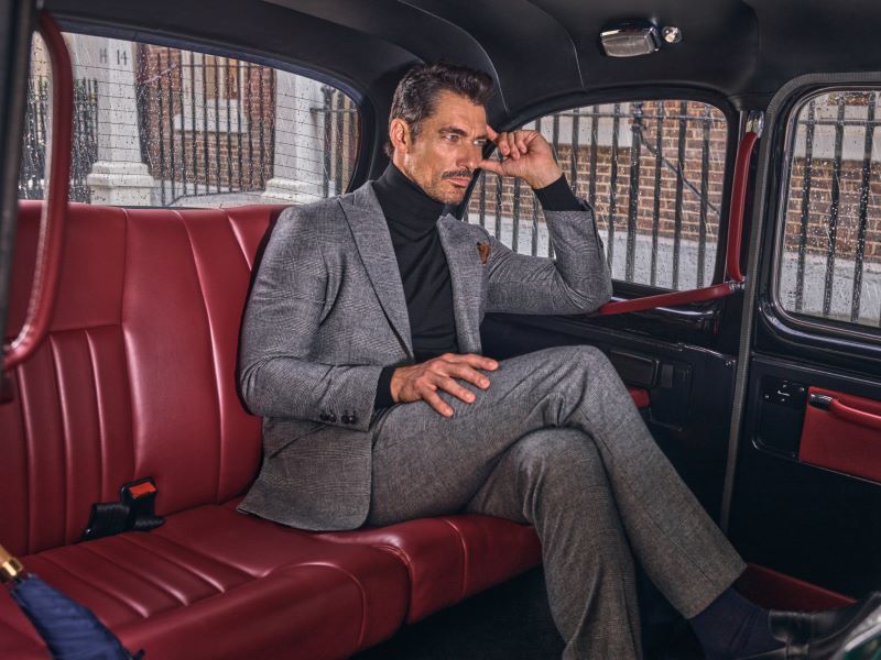 Homem elegante sentado em carro vermelho.