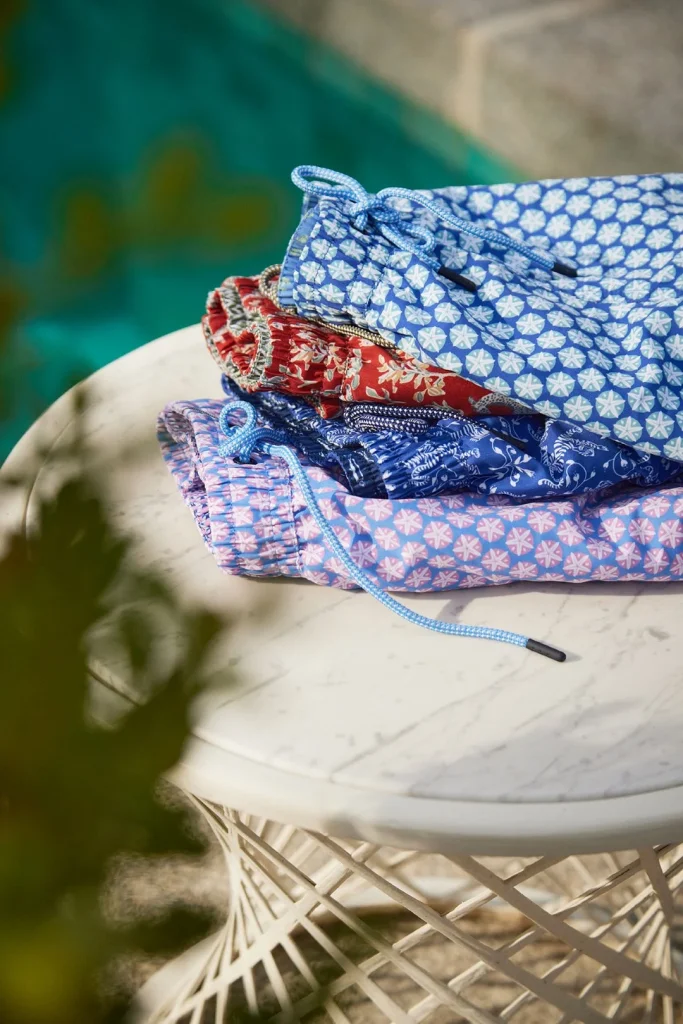 Pilha de calções de banho estampados numa mesa de mármore.