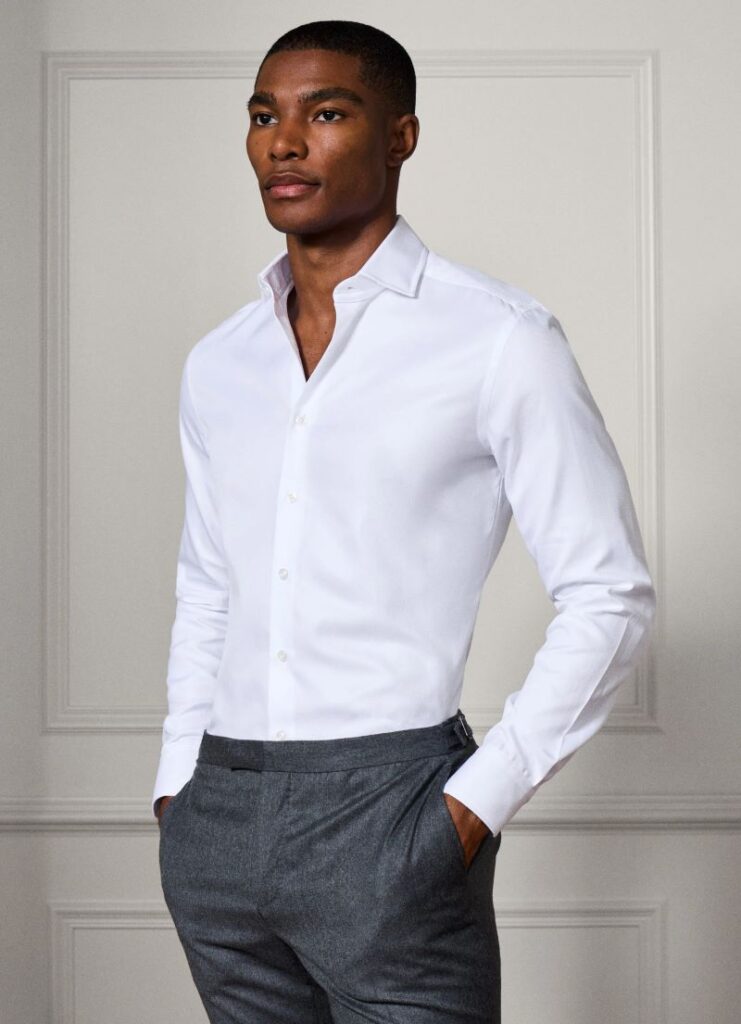 Homem elegante com camisa branca e calças cinzentas.
