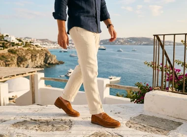 Homem caminha em terraço mediterrâneo com vista para o mar.