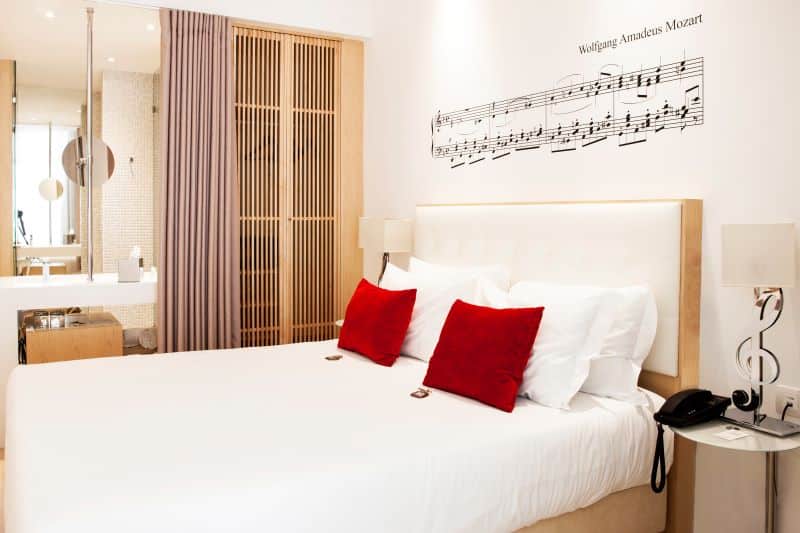 Quarto moderno com decoração musical e almofadas vermelhas.
