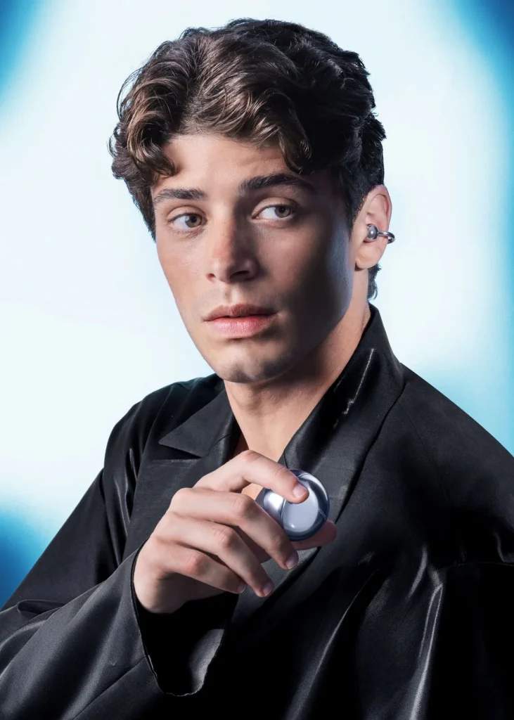 Homem jovem a usar auriculares prateados e a segurar estojo.
