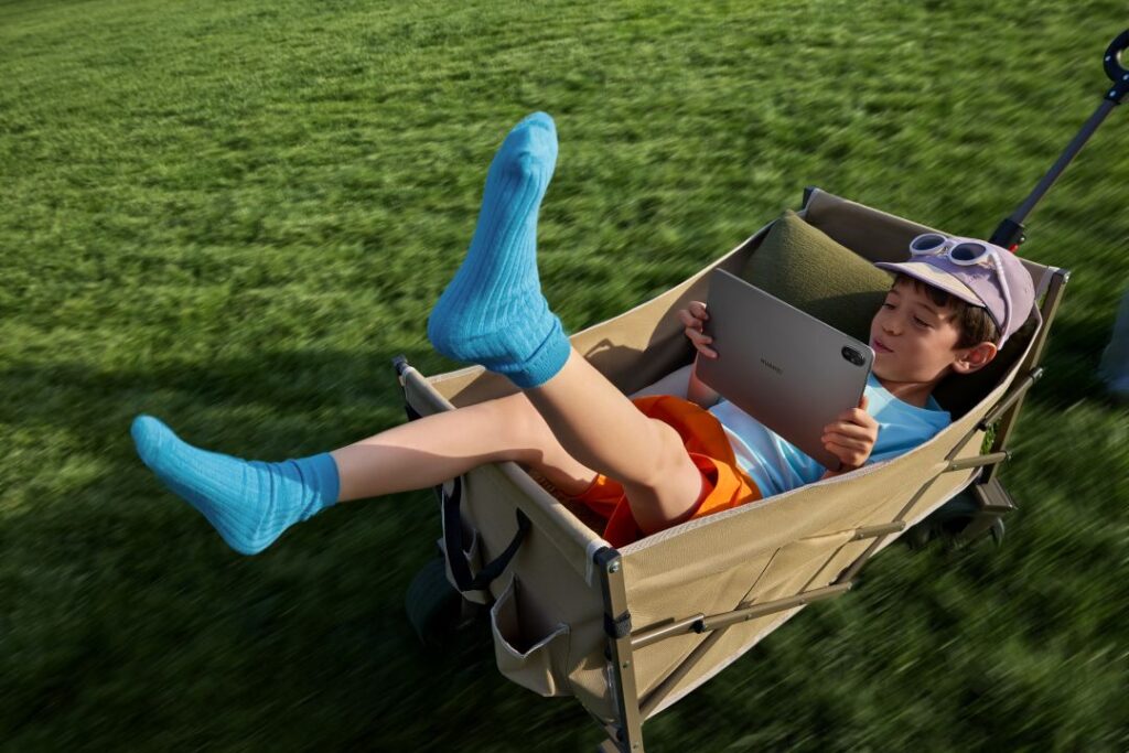 Criança relaxa num carrinho com tablet no parque.