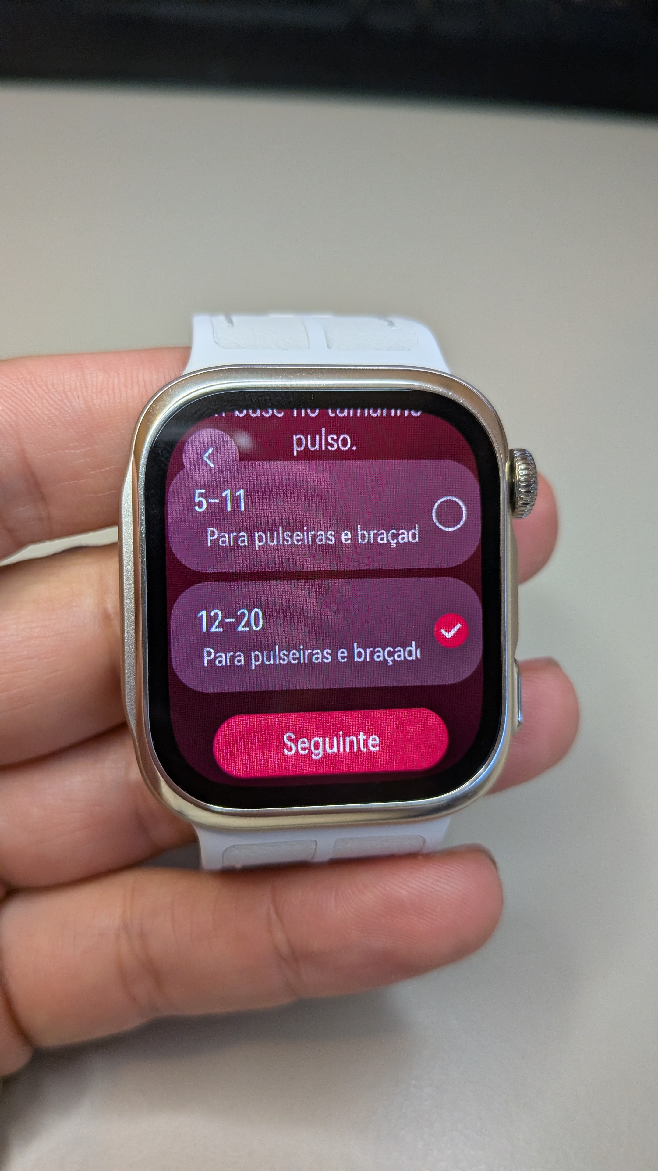 Mão a segurar o smartwatch Huawei Watch D3 branco com o ecrã a exibir as opções de tamanho de pulso para a braçadeira.
