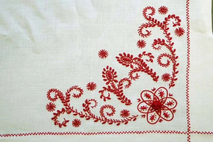 Bordado vermelho floral em tecido branco, artesanato tradicional português.