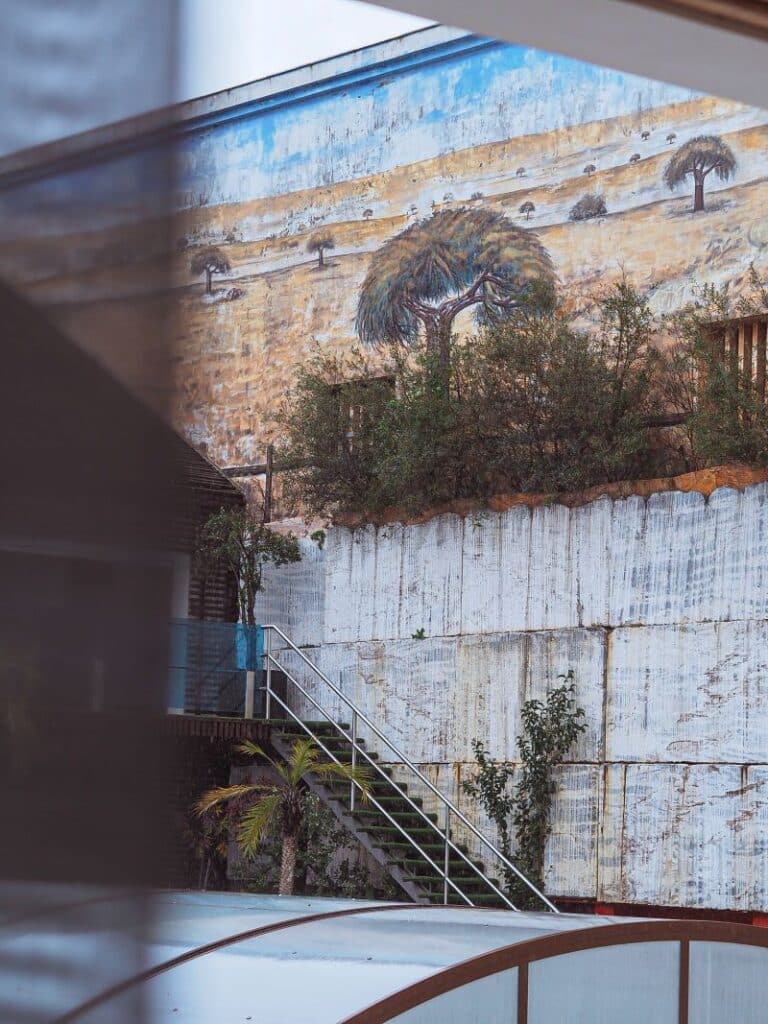 Mural de paisagem desértica com árvores e escadas.