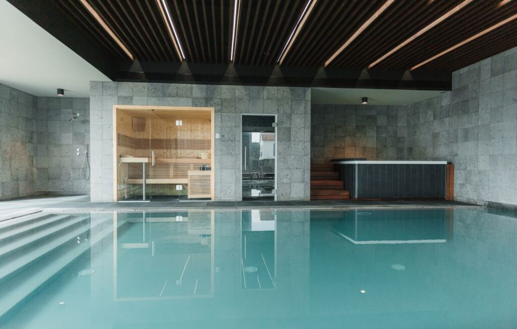 Piscina interior com sauna e jacuzzi ao lado.