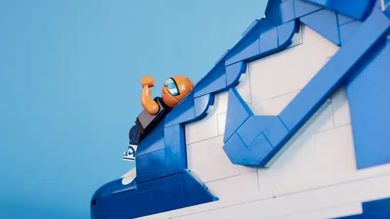 Figura Lego a escalar parede azul.