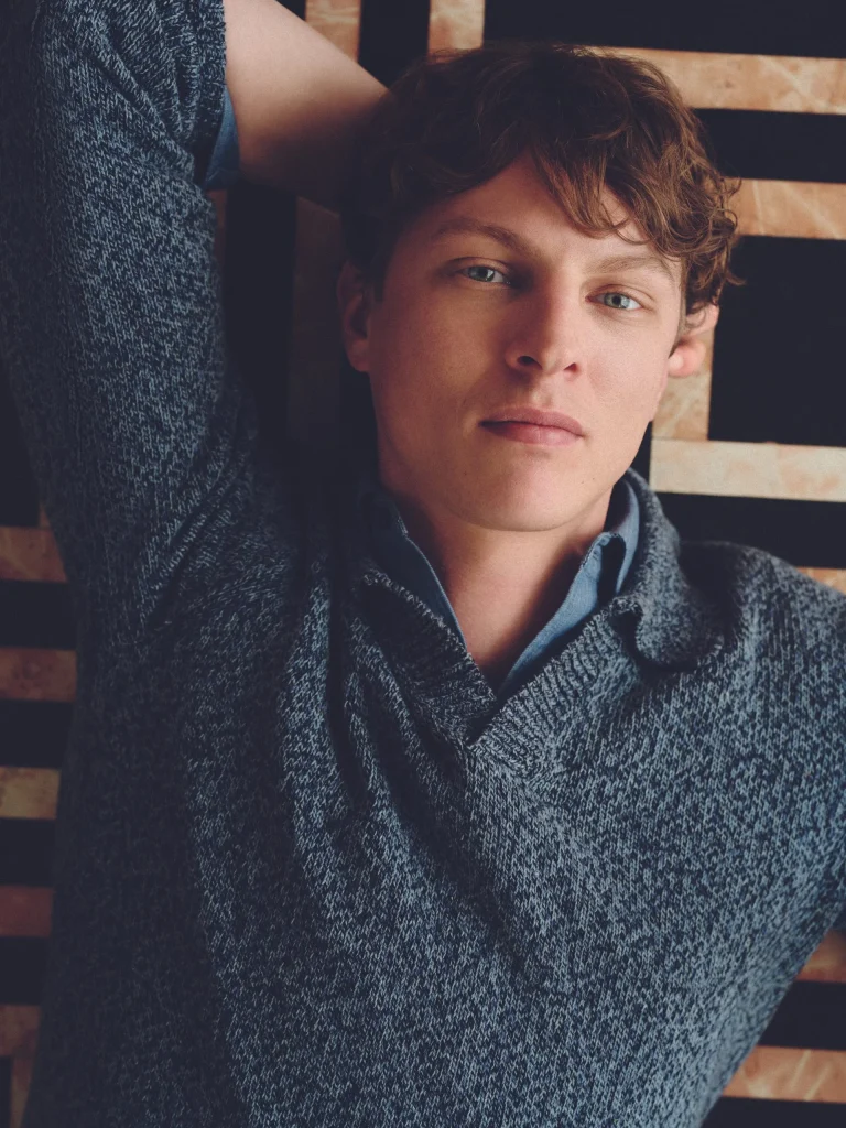 Homem de cabelo encaracolado com camisola de malha azul sobre camisa da coleção Mango Man Superior Denim
