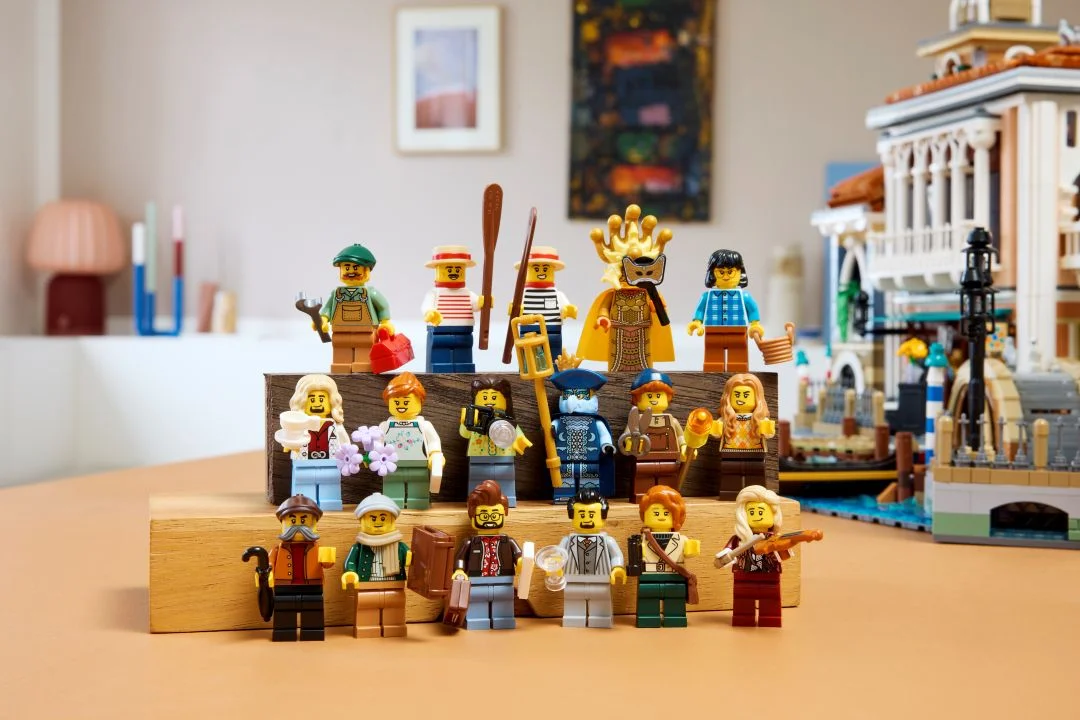 17 minifiguras do set LEGO Icons Bairro de Veneza dispostas em blocos de madeira com o diorama ao fundo