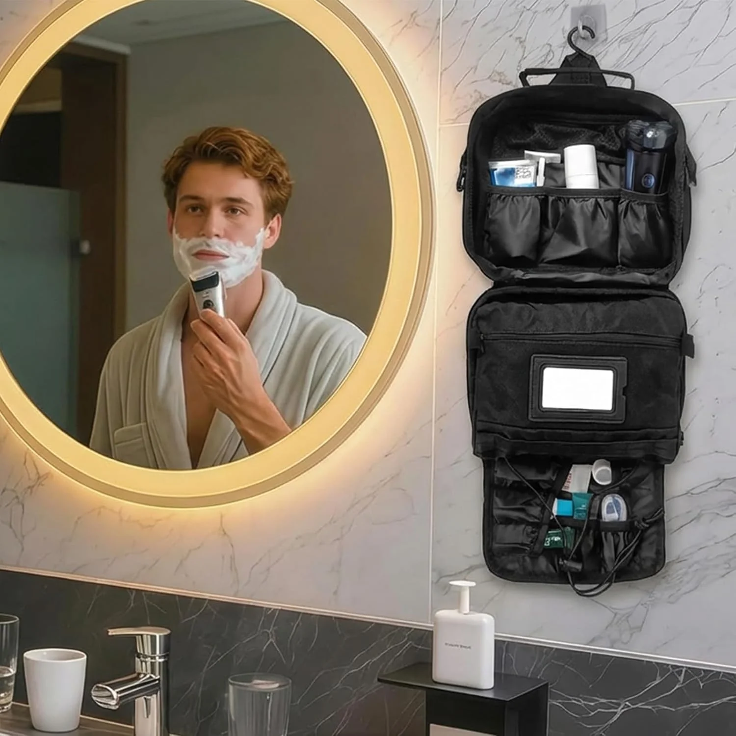 Homem a barbear-se em frente ao espelho com um necessaire de viagem preto suspenso na parede ao lado, aberto e organizado com produtos de higiene.