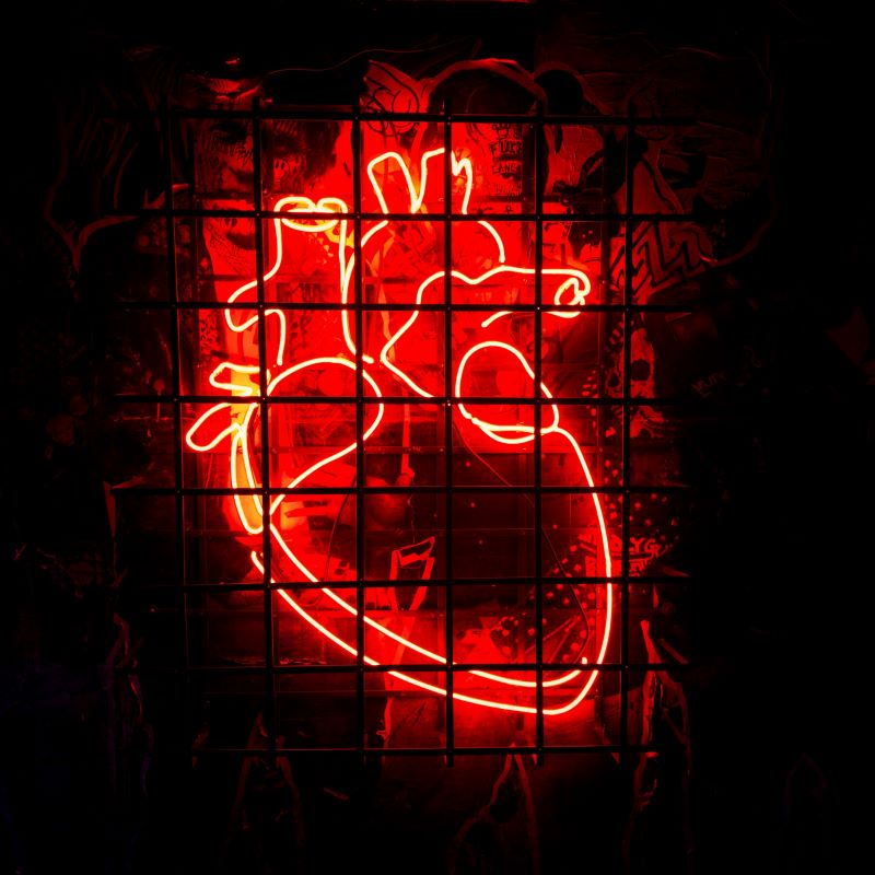 Coração neon vermelho atrás de grades, arte luminosa