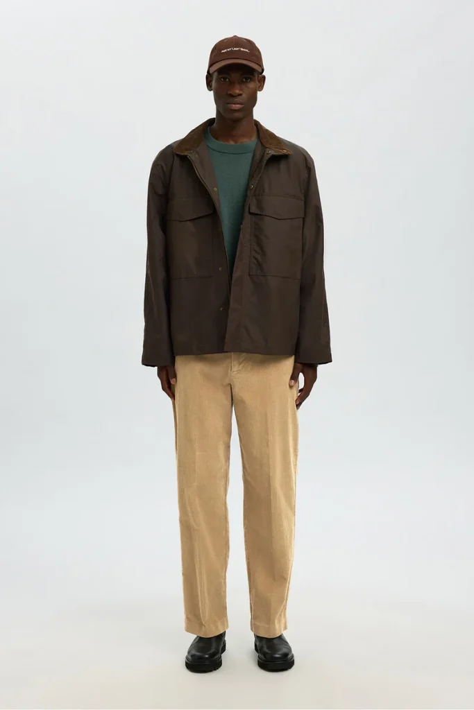 Homem usando casaco castanho e calças bege.