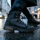 Botas de caminhada pretas num pavimento urbano molhado.
