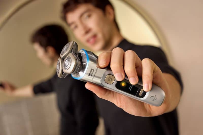Homem a segurar máquina de barbear elétrica.