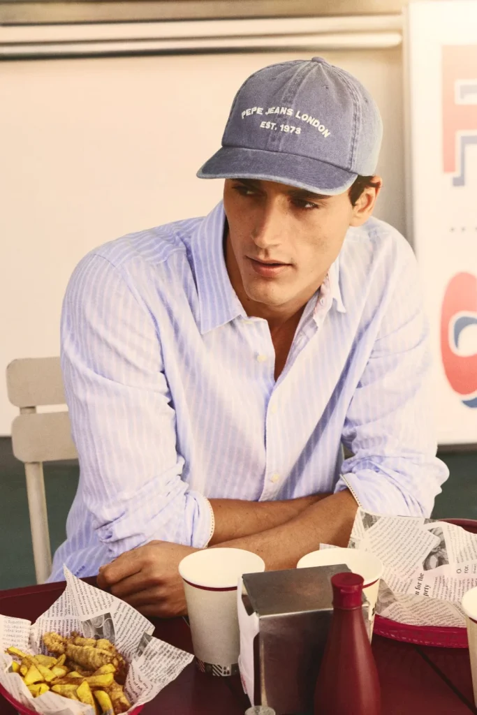 Homem de boné jeans e camisa às riscas numa refeição casual.