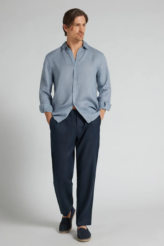 Homem com camisa de linho azul e calças azul-marinho.