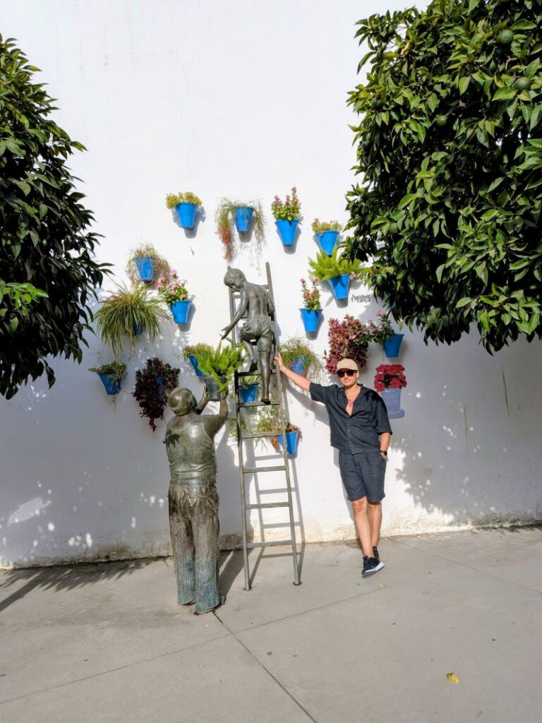 Escultura com vasos de flores na parede branca.