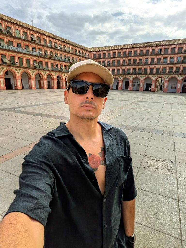 Homem com tatuagem num pátio histórico.
