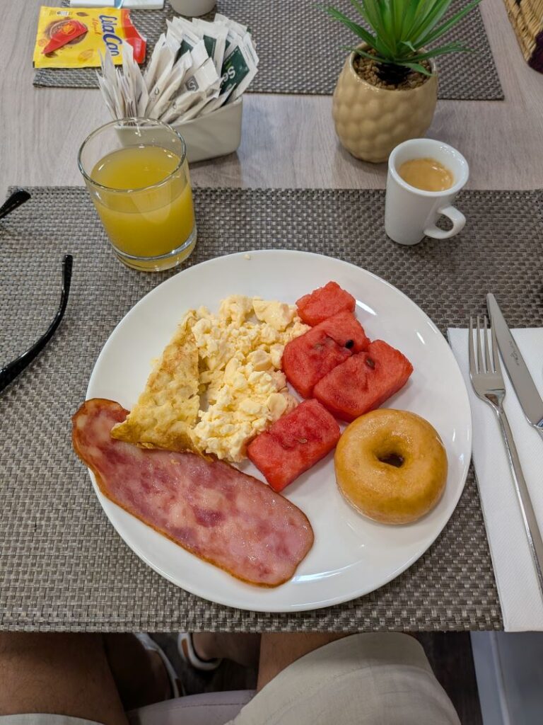 Pequeno-almoço com bacon, ovos, melancia e donut.