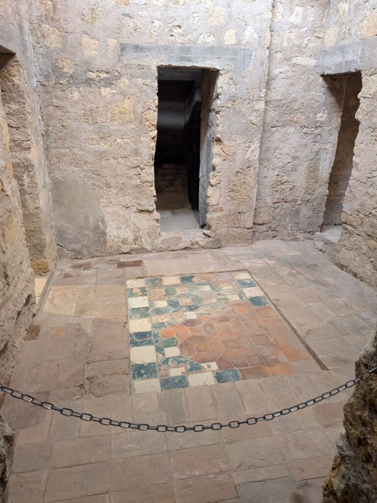 Sala antiga com piso de mosaico colorido.