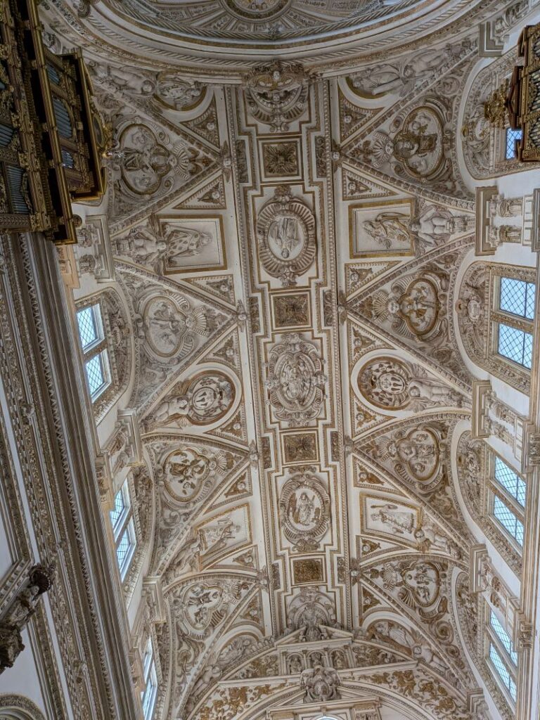 Teto decorado com esculturas e detalhes arquitetónicos.