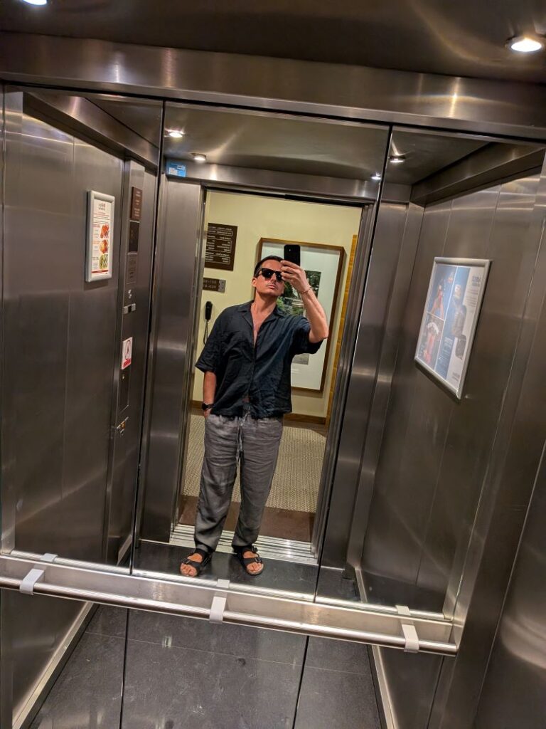 Pessoa a tirar selfie num elevador espelhado.