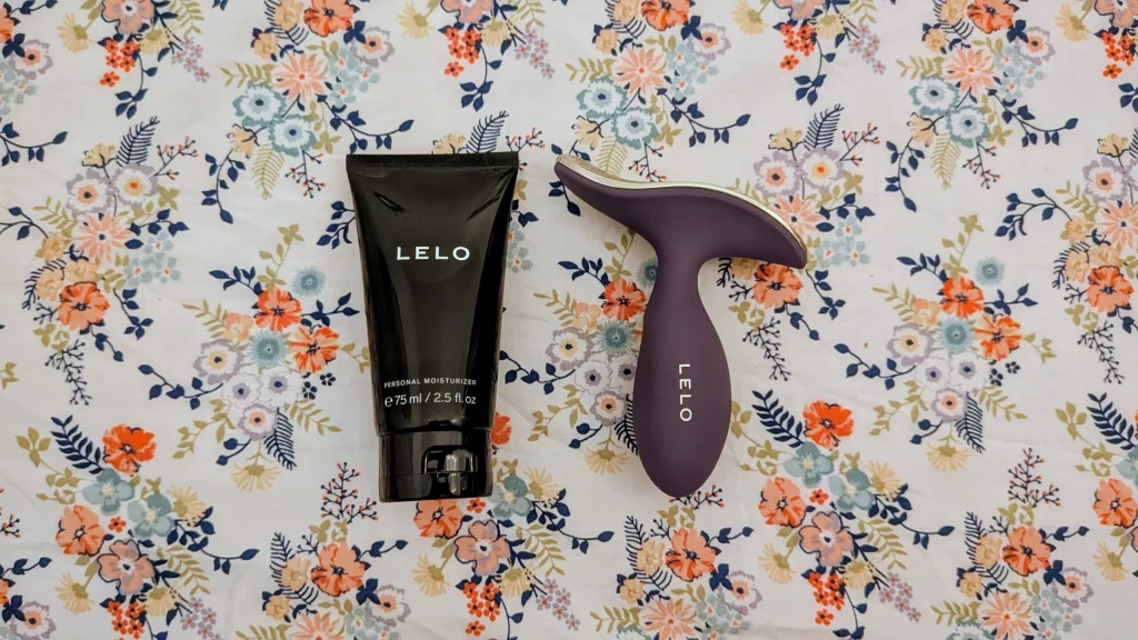Hidratante pessoal e vibrador LELO sobre fundo floral colorido.