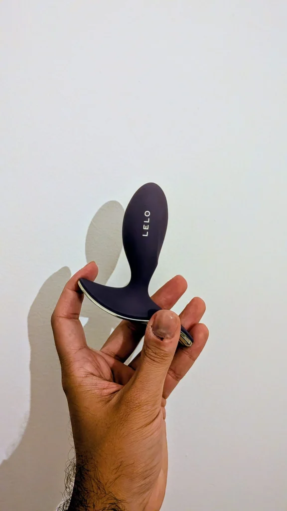 Mão a segurar um massajador pessoal roxo da marca LELO.
