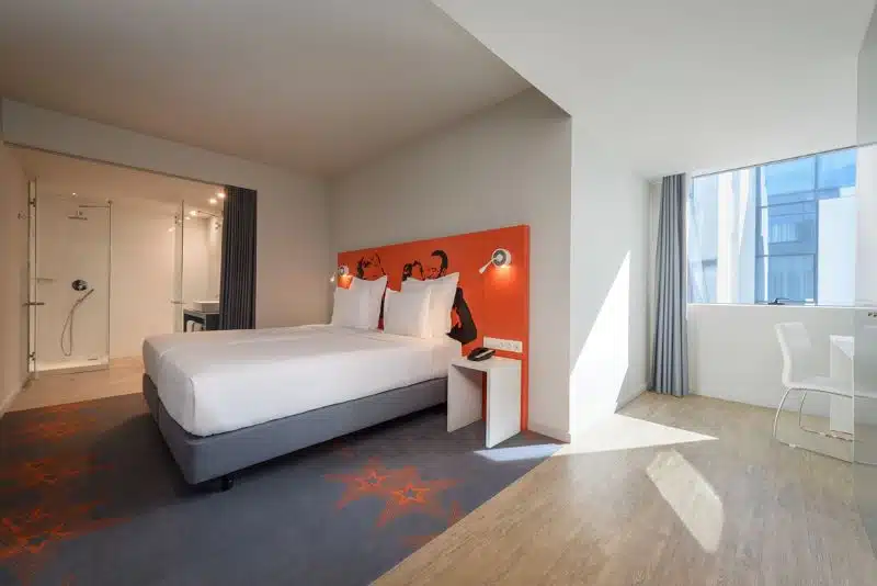 Quarto moderno com cama, janela e casa de banho.