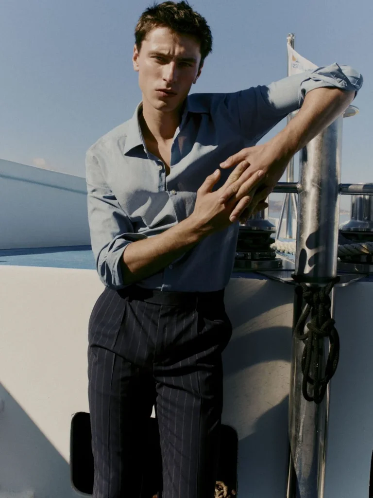 Homem elegante de camisa e calças listradas num barco.