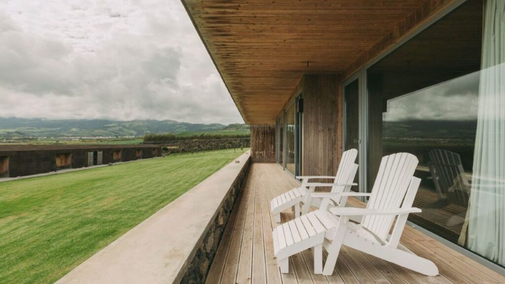Varanda de madeira com vista para o campo verde.