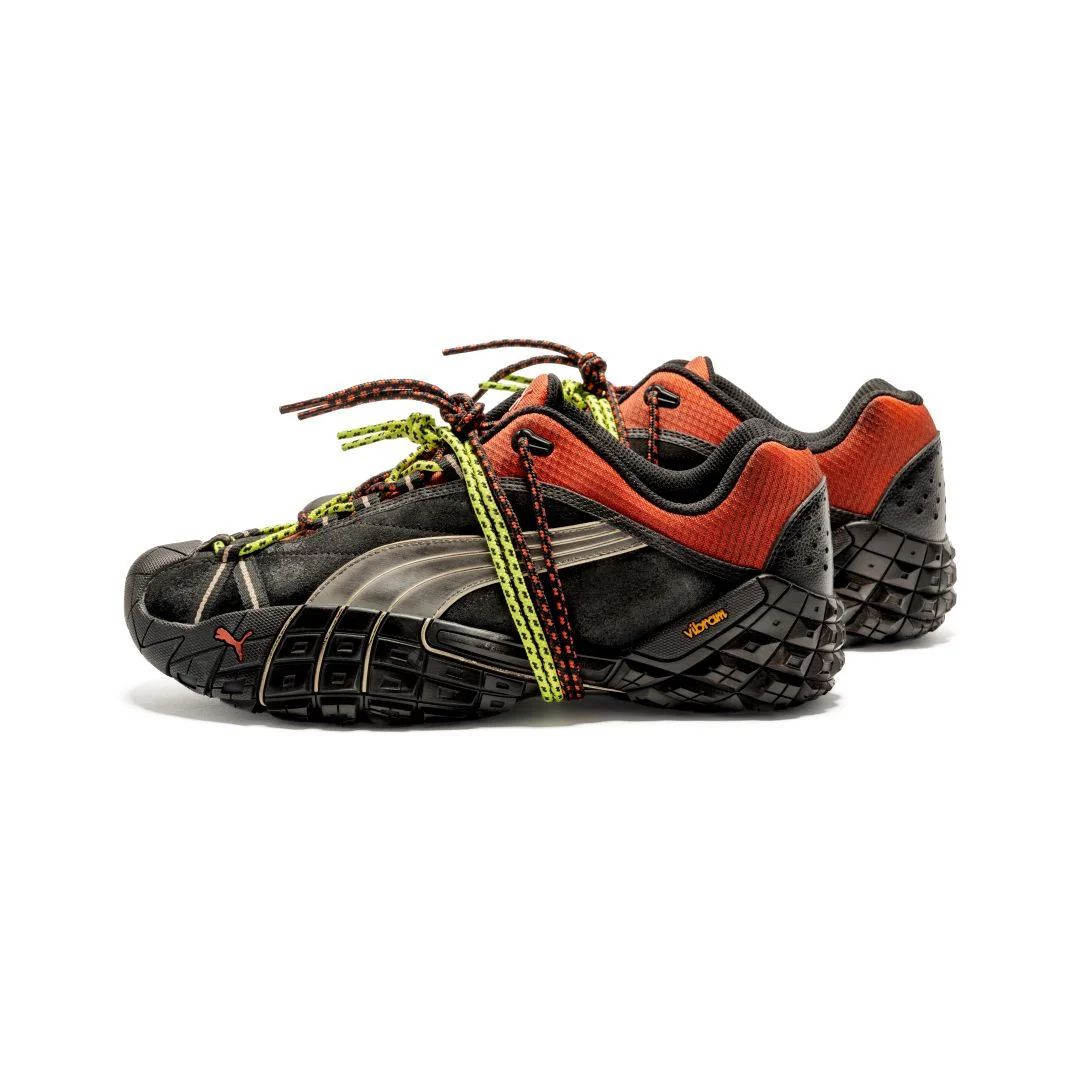 Sapatilhas Puma Straycat A$AP Rocky pretas e vermelhas com sola Vibram preta texturizada e atacadores duplos cruzados em amarelo e preto sobre fundo branco.