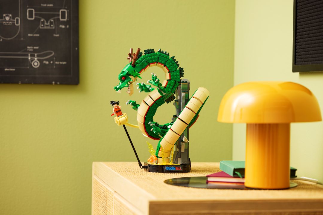 Set LEGO Dragon Ball montado com o dragão Shenron verde e a minifigura do Songoku na Nuvem Mágica, exposto num móvel de madeira ao lado de um candeeiro amarelo.