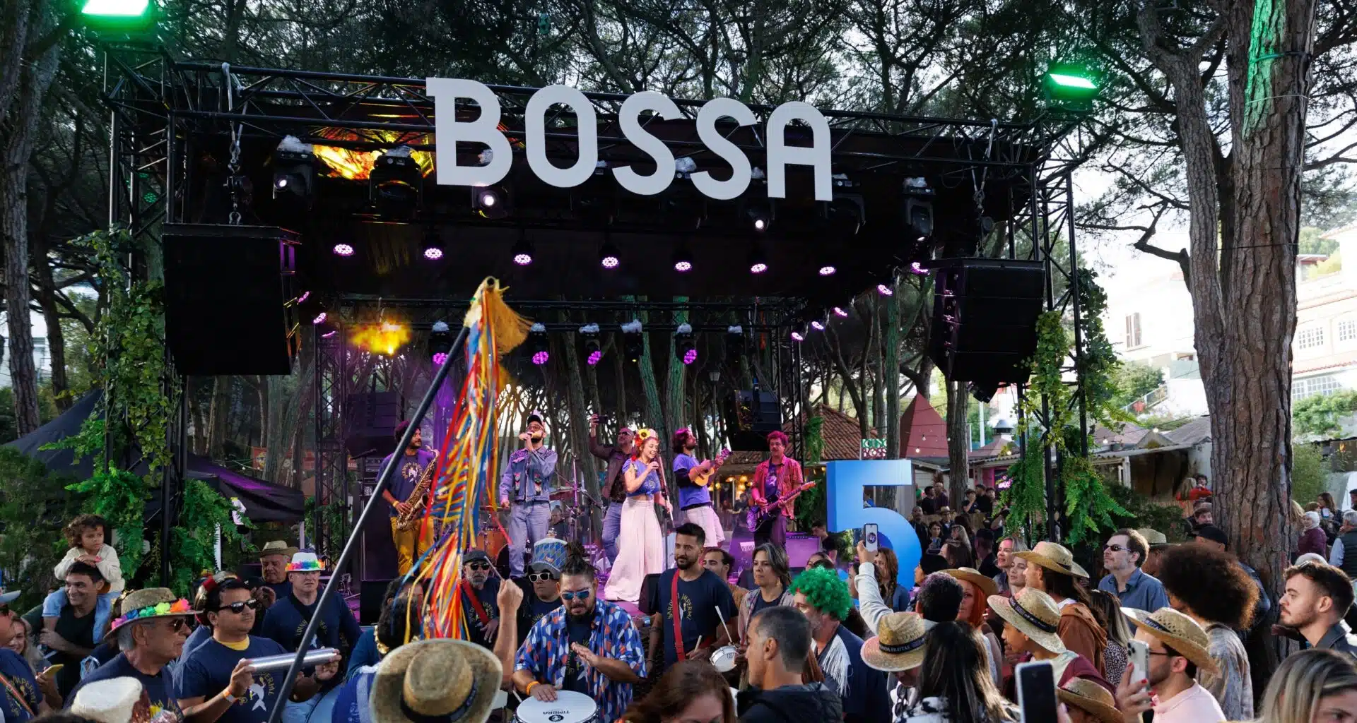 Concerto ao ar livre com banda e público animado.